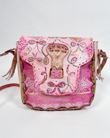 Émilie is a handpainted, up-cycled leather handbag by Mer Rose Atelier, pink is the  main color with ribbons, bows and lace designs.